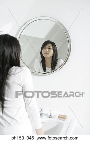 Rear view of a young woman looking in a mirror View Large Photo Image Stock Photograph - Rear view of a young woman looking in a mirror. Fotosearch