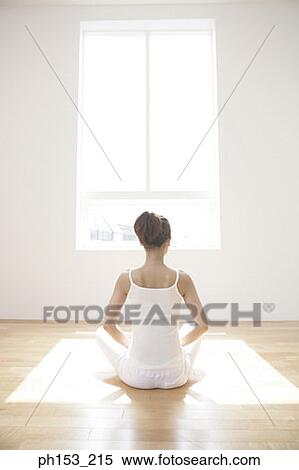 Stock Photography - Rear view of a young woman meditating. Fotosearch