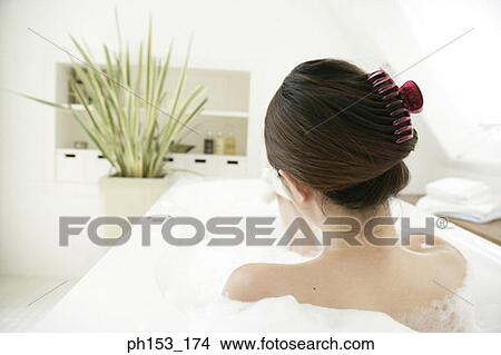 Rear view of a young woman relaxing in a bubble bath View Large Photo Image Picture - Rear view of a young woman relaxing in a bubble bath. Fotosearch