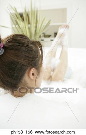 Rear view of a young woman relaxing in a bubble bath View Large Photo Image Stock Photograph - Rear view of a young woman relaxing in a bubble bath. Fotosearch