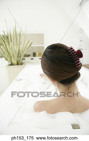 Stock Photography - Rear view of a young woman relaxing in a bubble bath. Fotosearch
