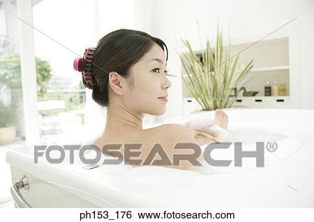 Rear view of a young woman scrubbing her leg in a bubble bath and smiling View Large Photo Image Stock Photograph - Rear view of a young woman scrubbing her leg in a bubble bath and smiling. Fotosearch