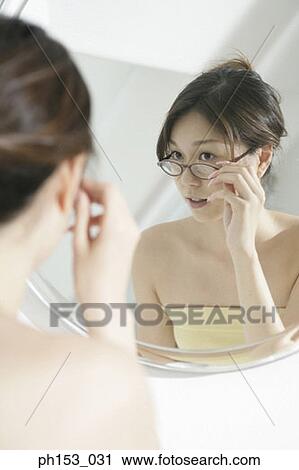 Reflection of a young woman adjusting her eyeglasses in a mirror View Large Photo Image Stock Image - Reflection of a young woman adjusting her eyeglasses in a mirror . Fotosearch