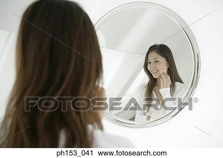 Reflection of a young woman applying face powder in a mirror View Large Photo Image Stock Image - Reflection of a young woman applying face powder in a mirror. Fotosearch