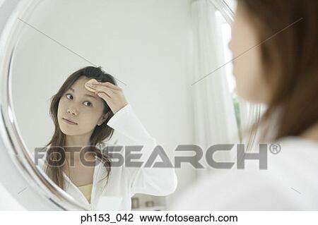 Reflection of a young woman applying face powder on her forehead in the mirror View Large Photo Image Stock Image - Reflection of a young woman applying face powder on her forehead in the mirror . Fotosearch