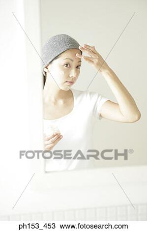 Reflection of a young woman applying moisturizer on her face View Large Photo Image Stock Image - Reflection of a young woman applying moisturizer on her face. Fotosearch