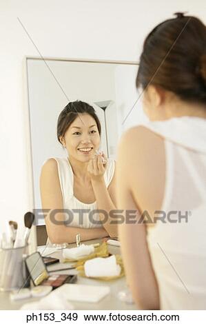 Reflection of a young woman applying lipstick in the mirror View Large Photo Image Stock Photo - Reflection of a young woman applying lipstick in the mirror . Fotosearch