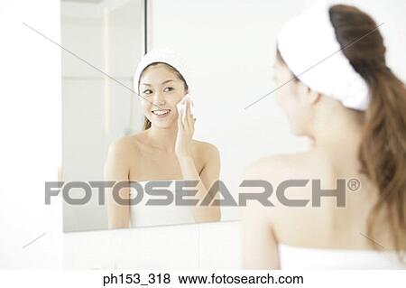 Reflection of a young woman cleaning her face with a tissue paper in the bathroom View Large Photo Image Stock Photo - Reflection of a young woman cleaning her face with a tissue paper in the bathroom. Fotosearch