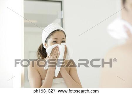 Reflection of a young woman drying her face with a towel in a mirror View Large Photo Image Stock Photo - Reflection of a young woman drying her face with a towel in a mirror . Fotosearch