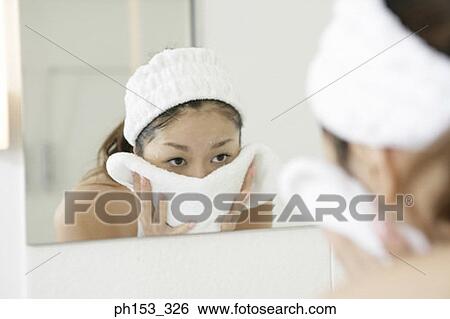 Reflection of a young woman drying her face with a towel in a mirror View Large Photo Image Stock Photograph - Reflection of a young woman drying her face with a towel in a mirror . Fotosearch