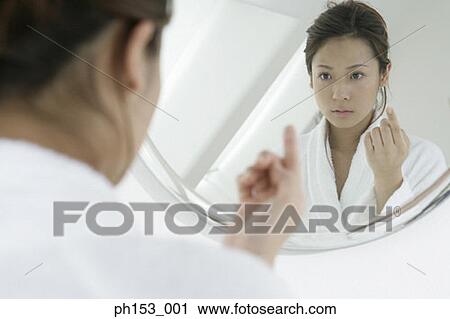 Stock Image - Reflection of a young woman in a mirror. Fotosearch