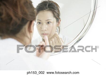 Stock Image - Reflection of a young woman in a mirror. Fotosearch