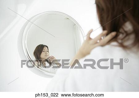 Stock Image - Reflection of a young woman in a mirror. Fotosearch