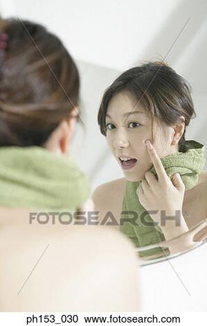 Reflection of a young woman in a mirror with her finger on her cheek View Large Photo Image Stock Image - Reflection of a young woman in a mirror with her finger on her cheek. Fotosearch