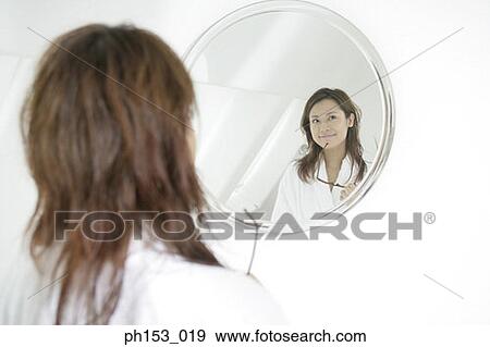 Reflection of a young woman in a mirror holding sunglasses View Large Photo Image Stock Photo - Reflection of a young woman in a mirror holding sunglasses. Fotosearch