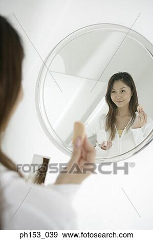 Reflection of a young woman in a mirror holding a powder puff and smiling View Large Photo Image Stock Photo - Reflection of a young woman in a mirror holding a powder puff and smiling. Fotosearch