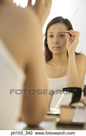 Reflection of a young woman tweezing her eyebrows in a mirror View Large Photo Image Stock Image - Reflection of a young woman tweezing her eyebrows in a mirror. Fotosearch