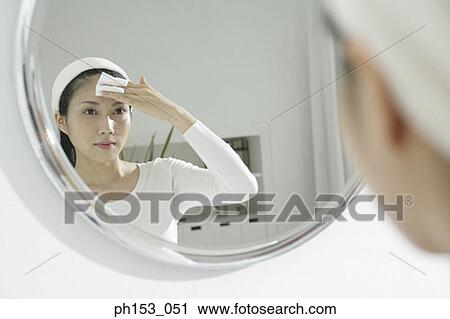 Reflection of a young woman wiping her forehead with a tissue paper in a mirror View Large Photo Image Stock Image - Reflection of a young woman wiping her forehead with a tissue paper in a mirror . Fotosearch
