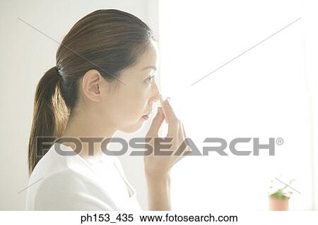 Side profile of a young woman applying face powder on her face View Large Photo Image Stock Photography - Side profile of a young woman applying face powder on her face. Fotosearch