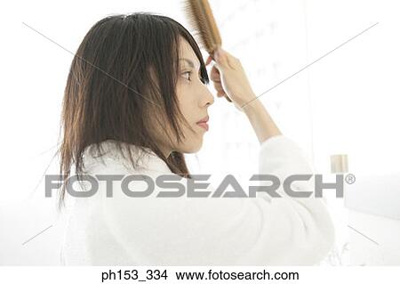 Side profile of a young woman brushing her hair View Large Photo Image Picture - Side profile of a young woman brushing her hair. Fotosearch