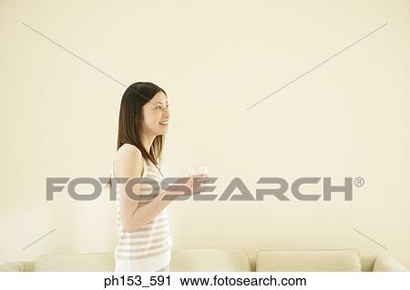 Side profile of a young woman holding a glass of water and smiling View Large Photo Image Stock Image - Side profile of a young woman holding a glass of water and smiling. Fotosearch