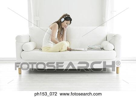 Side profile of a young woman listening to music and reading a magazine View Large Photo Image Stock Image - Side profile of a young woman listening to music and reading a magazine. Fotosearch
