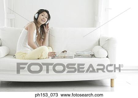 Stock Image - Side profile of a young woman listening to music and smiling. Fotosearch