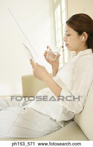 Side profile of a young woman listening to music on a couch and drinking water View Large Photo Image Stock Image - Side profile of a young woman listening to music on a couch and drinking water. Fotosearch
