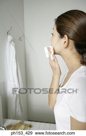 Side profile of a young woman wiping her cheek with a tissue paper View Large Photo Image Stock Photo - Side profile of a young woman wiping her cheek with a tissue paper. Fotosearch