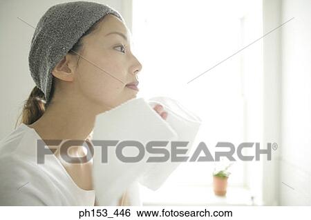 Side profile of a young woman wiping her face with a towel View Large Photo Image Stock Photograph - Side profile of a young woman wiping her face with a towel. Fotosearch