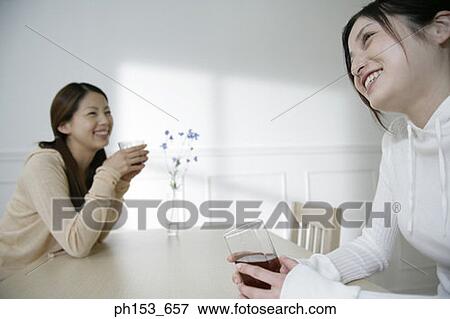 Stock Photo - Two young women drinking black tea at the dining table. Fotosearch