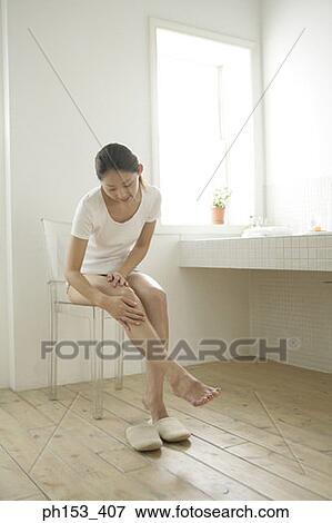 Young woman applying moisturizer on her leg in the bathroom View Large Photo Image Stock Photo - Young woman applying moisturizer on her leg in the bathroom. Fotosearch