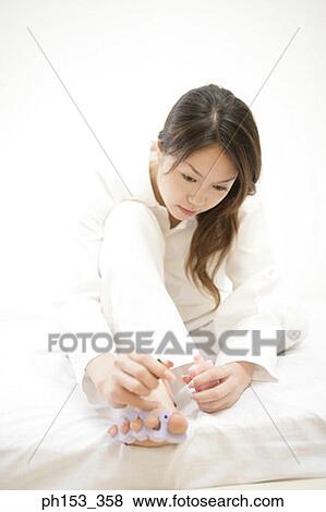 Young woman applying nail polish on her toenails View Large Photo Image Stock Photo - Young woman applying nail polish on her toenails. Fotosearch