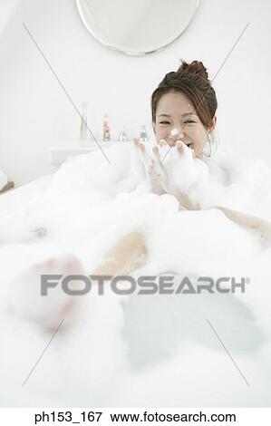 Young woman blowing foam in a bubble bath and looking cheerful View Large Photo Image Stock Photo - Young woman blowing foam in a bubble bath and looking cheerful. Fotosearch