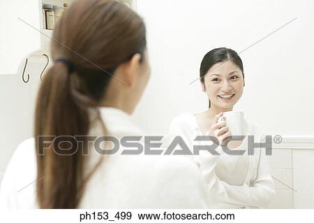 Young woman holding a coffee cup and looking at another young woman View Large Photo Image Stock Photo - Young woman holding a coffee cup and looking at another young woman. Fotosearch