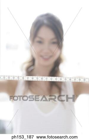 Young woman holding a tape measure View Large Photo Image Stock Photo - Young woman holding a tape measure. Fotosearch