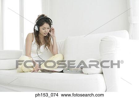 Young woman listening to music and reading a magazine View Large Photo Image Picture - Young woman listening to music and reading a magazine. Fotosearch