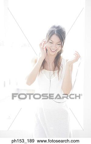 Young woman listening to music and smiling View Large Photo Image Stock Photo - Young woman listening to music and smiling. Fotosearch