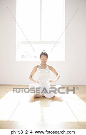 Picture - Young woman sitting in the lotus position and looking cheerful. Fotosearch