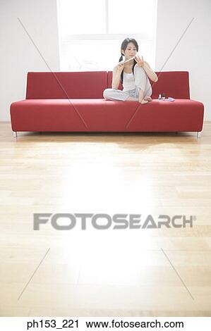Young woman sitting on a couch and filing her fingernails View Large Photo Image Stock Image - Young woman sitting on a couch and filing her fingernails. Fotosearch