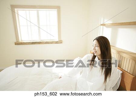 Young woman sitting on the bed View Large Photo Image Stock Image - Young woman sitting on the bed. Fotosearch