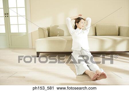 Stock Image - Young woman sitting on the floor and smiling. Fotosearch