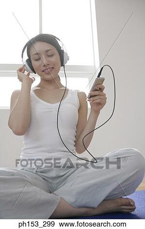 Young woman sitting with cross-legged and listening to music View Large Photo Image Stock Photo - Young woman sitting with cross-legged and listening to music. Fotosearch