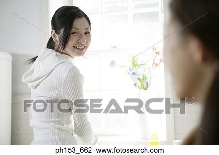 Young woman smiling and looking at her sister View Large Photo Image Stock Image - Young woman smiling and looking at her sister. Fotosearch