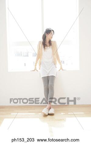 Young woman standing near a window and thinking View Large Photo Image Stock Image - Young woman standing near a window and thinking. Fotosearch