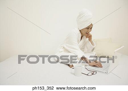 Young woman using a laptop on the bed and smiling View Large Photo Image Stock Image - Young woman using a laptop on the bed and smiling. Fotosearch