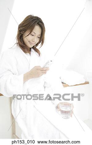 Young woman using a mobile phone in the bathroom View Large Photo Image Stock Image - Young woman using a mobile phone in the bathroom. Fotosearch