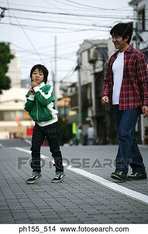 Boy eating candy with his father walking behind him View Large Photo Image Picture - Boy eating candy with his father walking behind him. Fotosearch