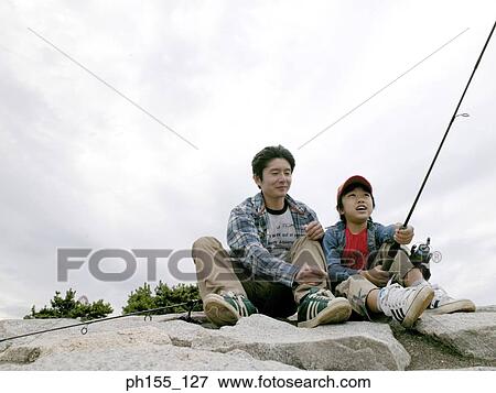 Stock Photo - Boy holding a fishing rod with his father beside him. Fotosearch