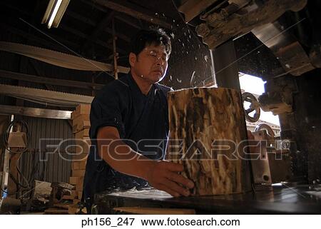 Stock Photo - Carpenter cutting wood in a workshop. Fotosearch